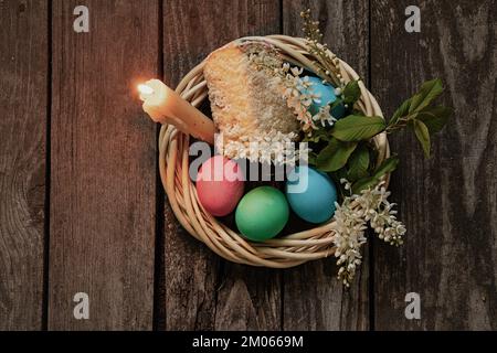 Easter dinner, colored chicken eggs and candle flame on an old wooden table in the evening Stock Photo