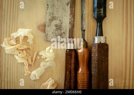 Traditional carpenter's tools on light wooden table; a saw and two chisels Stock Photo