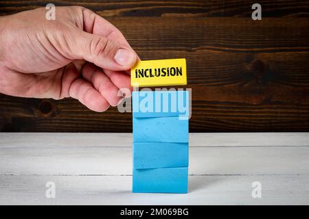 Inclusion. Blue wooden blocks in a pile and yellow block with text on top. Stock Photo