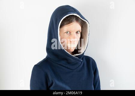 Girl with her mouth sealed with duct tape over isolated background ,be quiet and don't say anything,secret Stock Photo