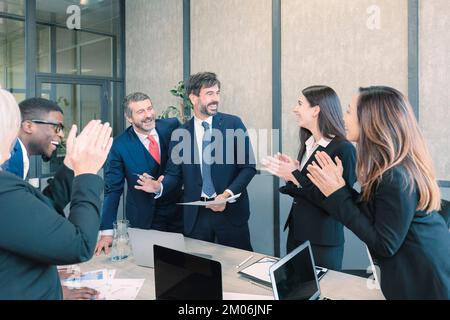 Group of multiethnic workers smiling happy and confident. Working together with a smile on your face applauding one of them in the office Stock Photo