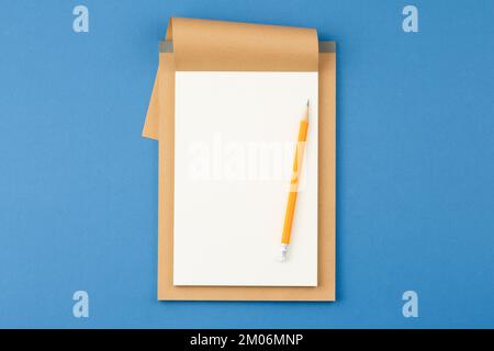 Notepad with pencil on blue background. Stock Photo
