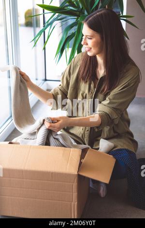 Vertical photo of women holding a wooled scarf she just took out of the box, the mailman brought to her  Stock Photo