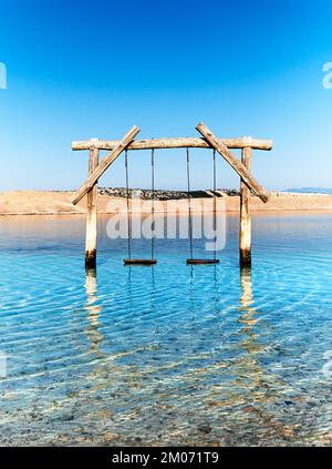 Empty swing in the water. Pebble beach on Adriatic coast of Croatia. Island Krk on background. Jadranovo village near Rijeka in Dalmatia, Croatia. Rom Stock Photo