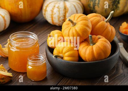 Two jars of healthy pumpkin jam and wooden bowl of pumpkins. Stock Photo