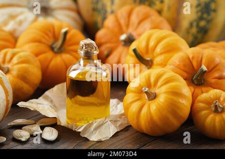 Healthy pumpkin seeds oil bottle, pumpkins on wooden kitchen table. Stock Photo