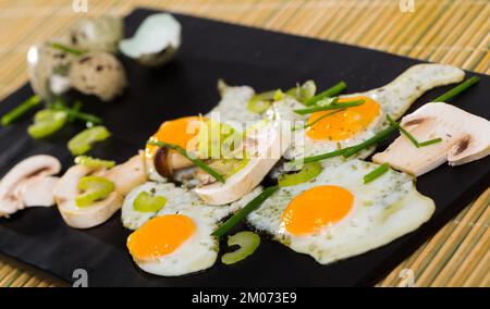 Fried quail eggs with champignons Stock Photo