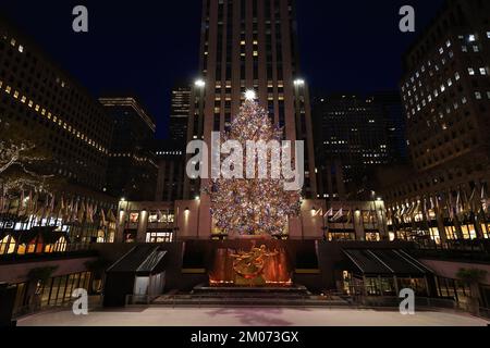 The Rockefeller Center Christmas Tree shines brightly as crowds gather to take photos as the Comcast Building illuminates in the background. Stock Photo