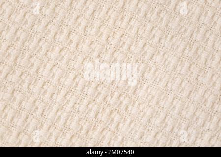 Beige knitted throw fabric texture background, machine knitting texture. Light bedcover closeup Stock Photo
