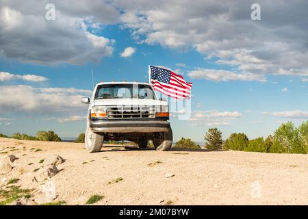 Old Truck with an American Flag Waving in the Wind Stock Photo