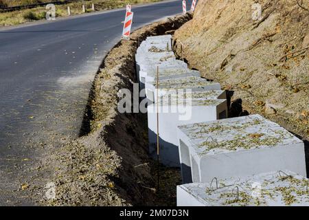 Installing precast u-shape concrete drains along reconstruction road for purpose of draining ground Stock Photo