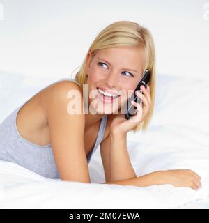Long lost friend calling to say hi. A young woman talking on the phone while in bed. Stock Photo