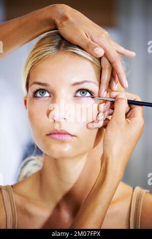 Creating a dramatic eye. Pretty young woman having her makeup applied by a stylist. Stock Photo