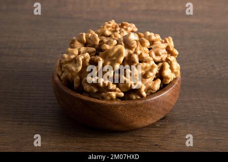 Bowl full of peeled walnuts on a wooden background Stock Photo
