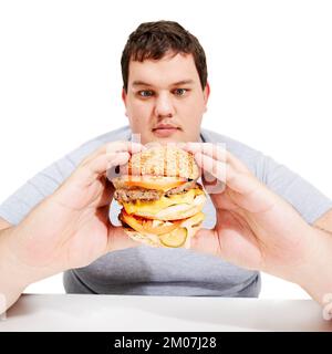 Hello burger Youre about to be eaten. A young obese man looking yearningly at the burger he is holding. Stock Photo