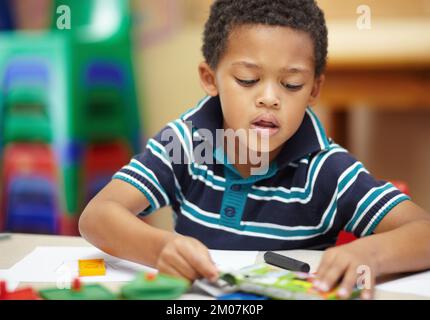 Expanding his creativity. Pre-school african american boy concentrating on his drawings with his crayons and shapes. Stock Photo