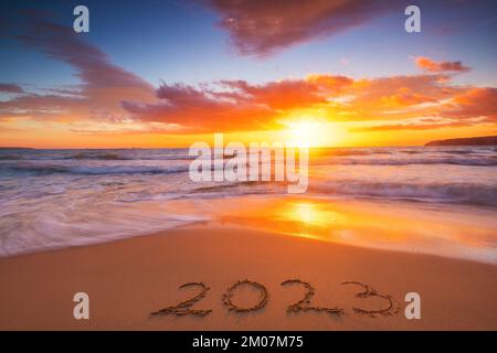 Happy New Year 2023 travel and lifestyle concept, text lettering on the beach shore. Ocean sunrise. Sea sunset. Stock Photo