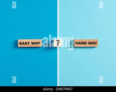 The words easy way and hard way on wooden blocks with question mark symbol. Dilemma or choice between choosing the easy or hard way concept. Stock Photo