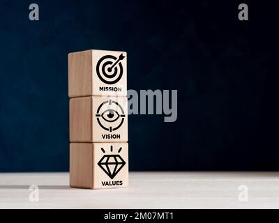 Mission, vision and values of a company. Stacked wooden cubes with business mission, vision and values symbols. Stock Photo