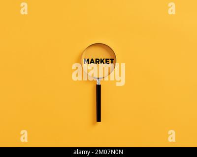 Magnifying glass or magnifier focusing on the word market. Business market strategy or focusing on target market analysis concept. Stock Photo