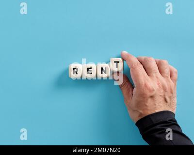 Male hand arranging wooden cubes with the word rent. Housing, house rental or real estate search. Stock Photo