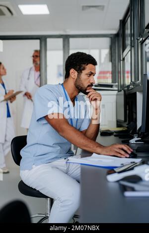 Portrait of young doctor working on computer in his office. Stock Photo