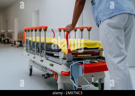 Rear view of caregiver pushing hospital bed at corridor. Stock Photo