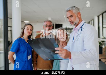 Doctor showing x-ray image to patients, explaining diagnosis. Stock Photo