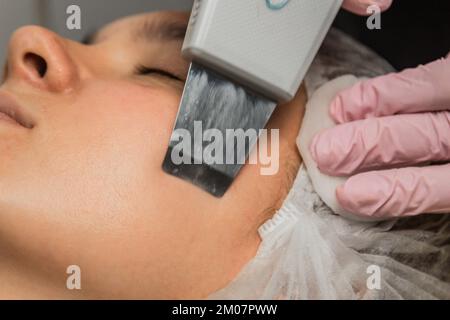 close-up. Ultrasonic face cleaning. Modern equipment. Beautician does cosmetic procedure on woman face Stock Photo