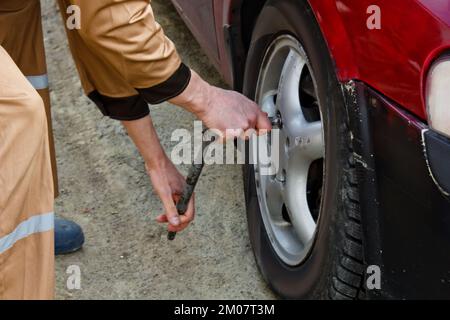 Auto mechanic man with electric screwdriver changing tire outside. Car service. Hands replace tires on wheels. Tire installation concept Stock Photo
