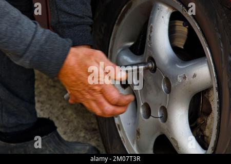 Auto mechanic man with electric screwdriver changing tire outside. Car service. Hands replace tires on wheels. Tire installation concept Stock Photo