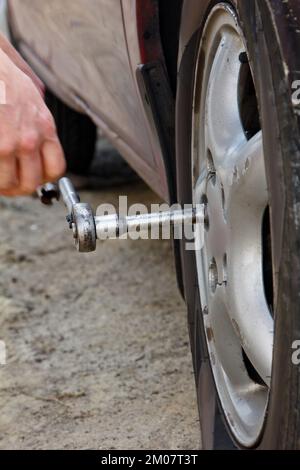Auto mechanic man with electric screwdriver changing tire outside. Car service. Hands replace tires on wheels. Tire installation concept Stock Photo
