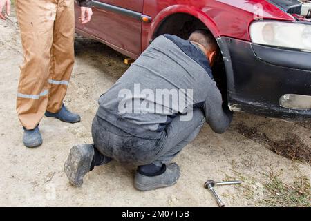 Service process. A man holds a tire in the garage. Replacing winter and summer tires. Seasonal tire replacement concept Stock Photo