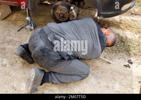 Service process. A man holds a tire in the garage. Replacing winter and summer tires. Seasonal tire replacement concept Stock Photo