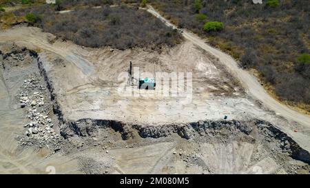 An aerial shot of a blue machine for placing explosives in a cement quarry Stock Photo