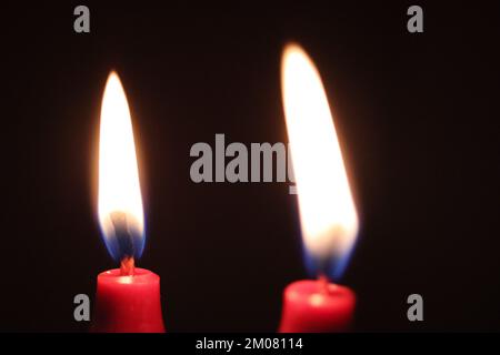A closeup of two red candles burning in the dark Stock Photo