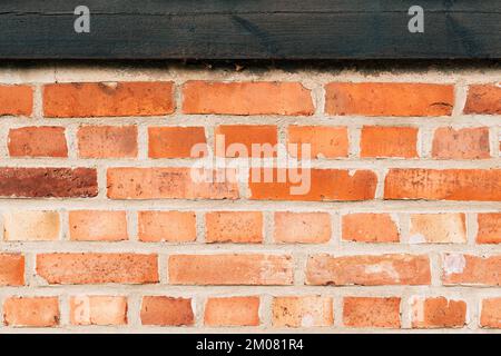 Rustic brick wall with old wooden joist as background. Detail from Halmstad, Sweden. Stock Photo
