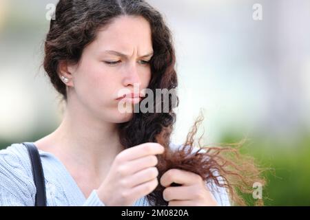 Angry woman cheking hair split ends in the street Stock Photo