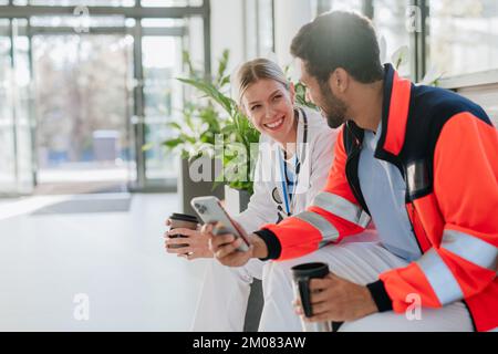 Rescuer having break and talking with doctor colleague, at hospital corridor. Stock Photo