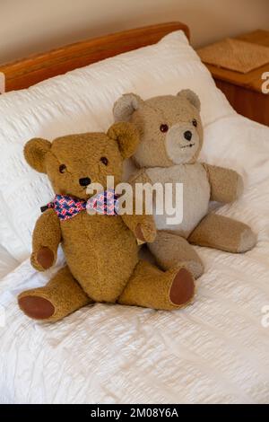 Two teddy bears sitting on a bed Stock Photo