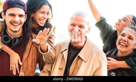 Trendy people walking together on piggyback move - Life style concept with happy young friends having cool fun around city streets Stock Photo
