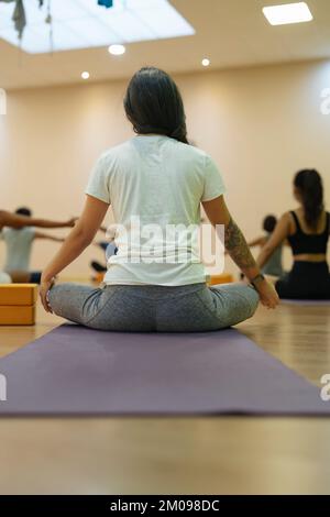 Photo of young brunette doing yoga in bathtub in apartment in