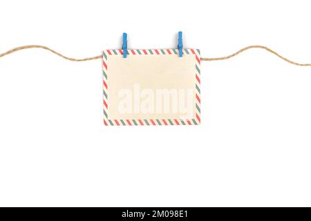 An empty postcard hangs on a rope on a clothespin on a white background. Stock Photo