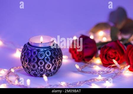 Burning candle and bouquet of roses in neon light, valentine's day concept. Stock Photo