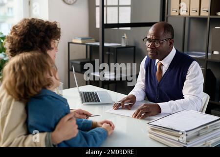 Portrait of senior black man as attorney consulting mother and child on insurance policy Stock Photo