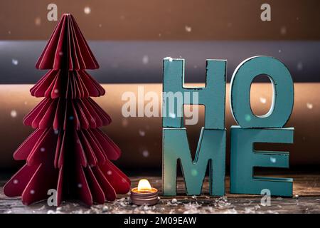Cozy winter composition with decorative word home and paper christmas tree. Stock Photo