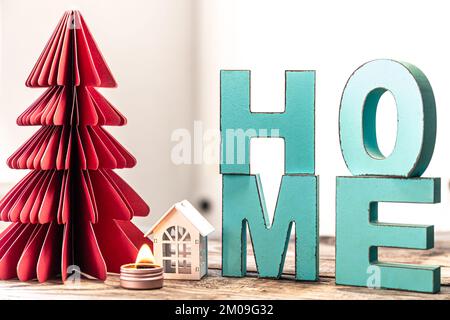 Cozy winter composition with decorative word home and paper christmas tree. Stock Photo