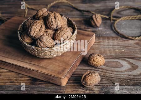Close-up, whole walnuts in a wicker bowl on a wooden background. Stock Photo