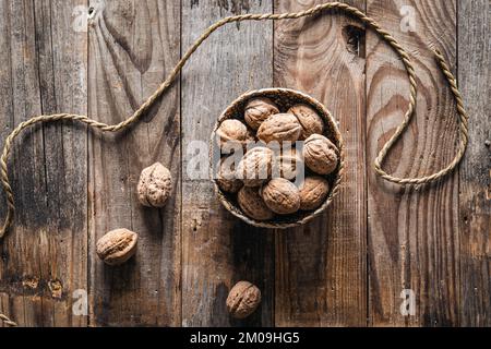 Bowl with whole walnuts on wooden background, flat lay. Stock Photo