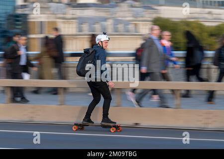 A man commuting during rush hour on an e-skateboard across, London Bridge, London, UK.  18 Oct 2022 Stock Photo